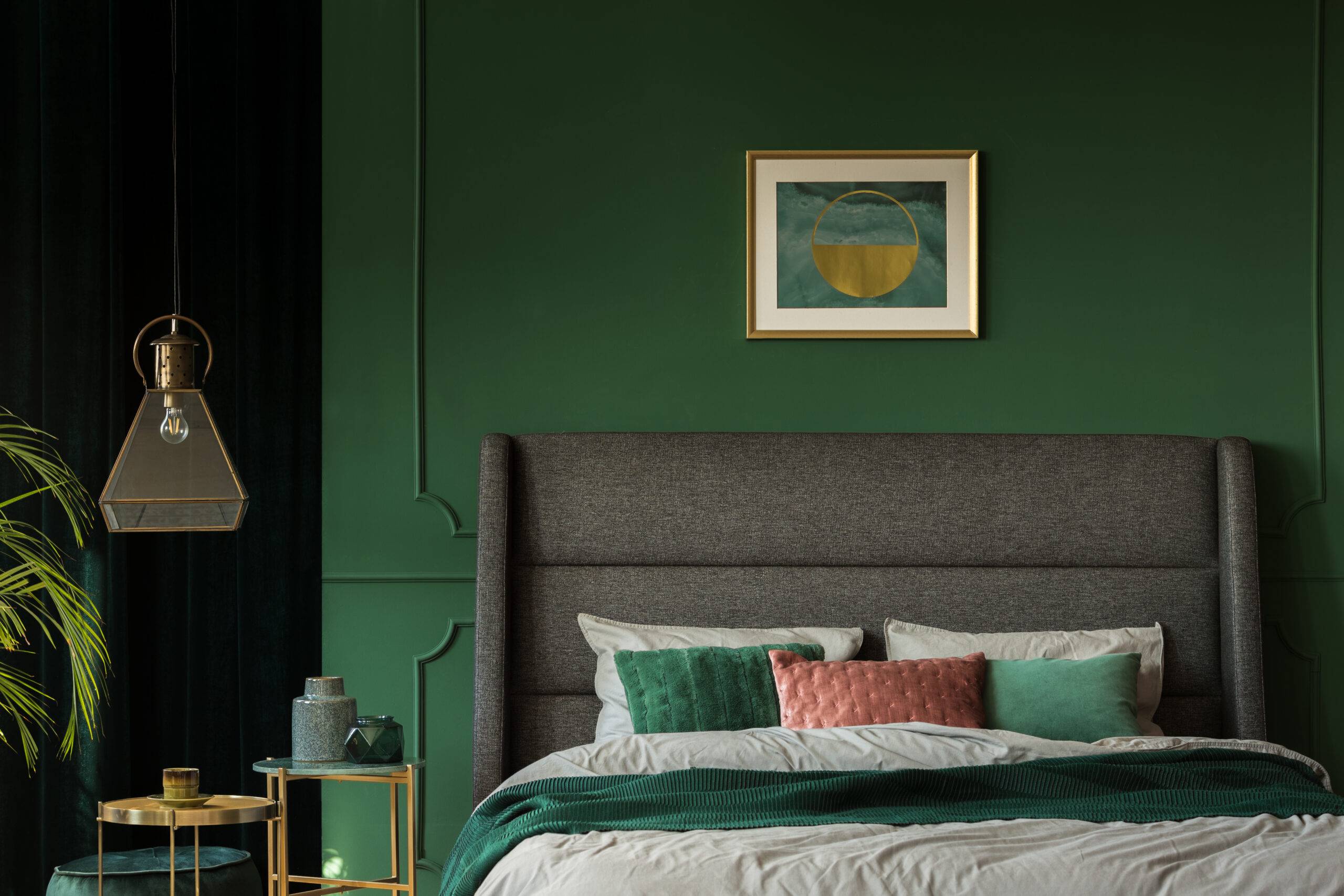 Stylish poster above comfortable king size bed with headboard in dark green bedroom