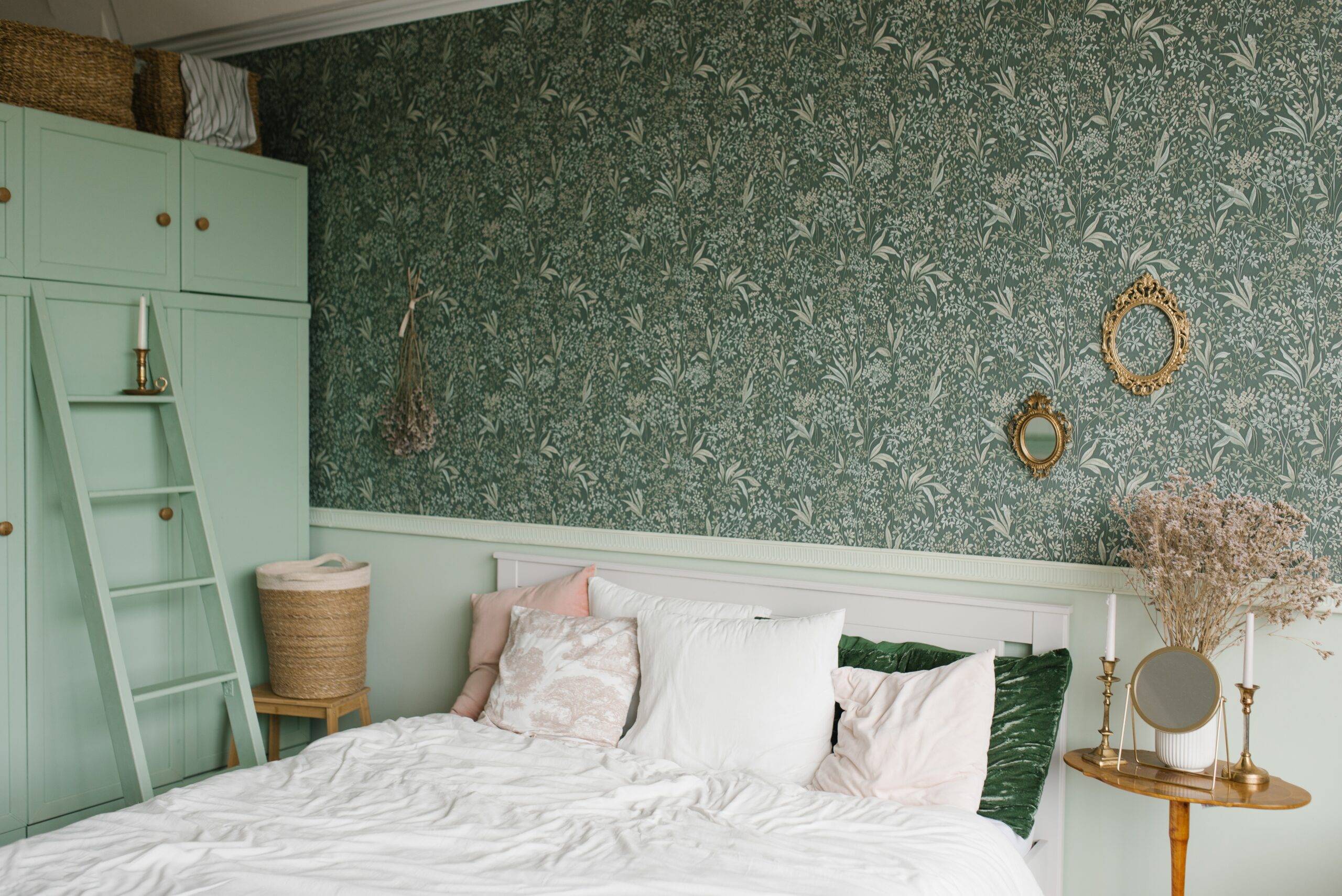 The interior of a classic bedroom. A bed with pillows and a wooden bedside table with dried flowers in a vase