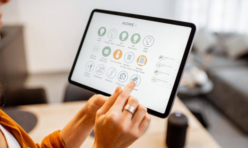 A woman holding up a tablet with a number of smart home controls up on the screen.