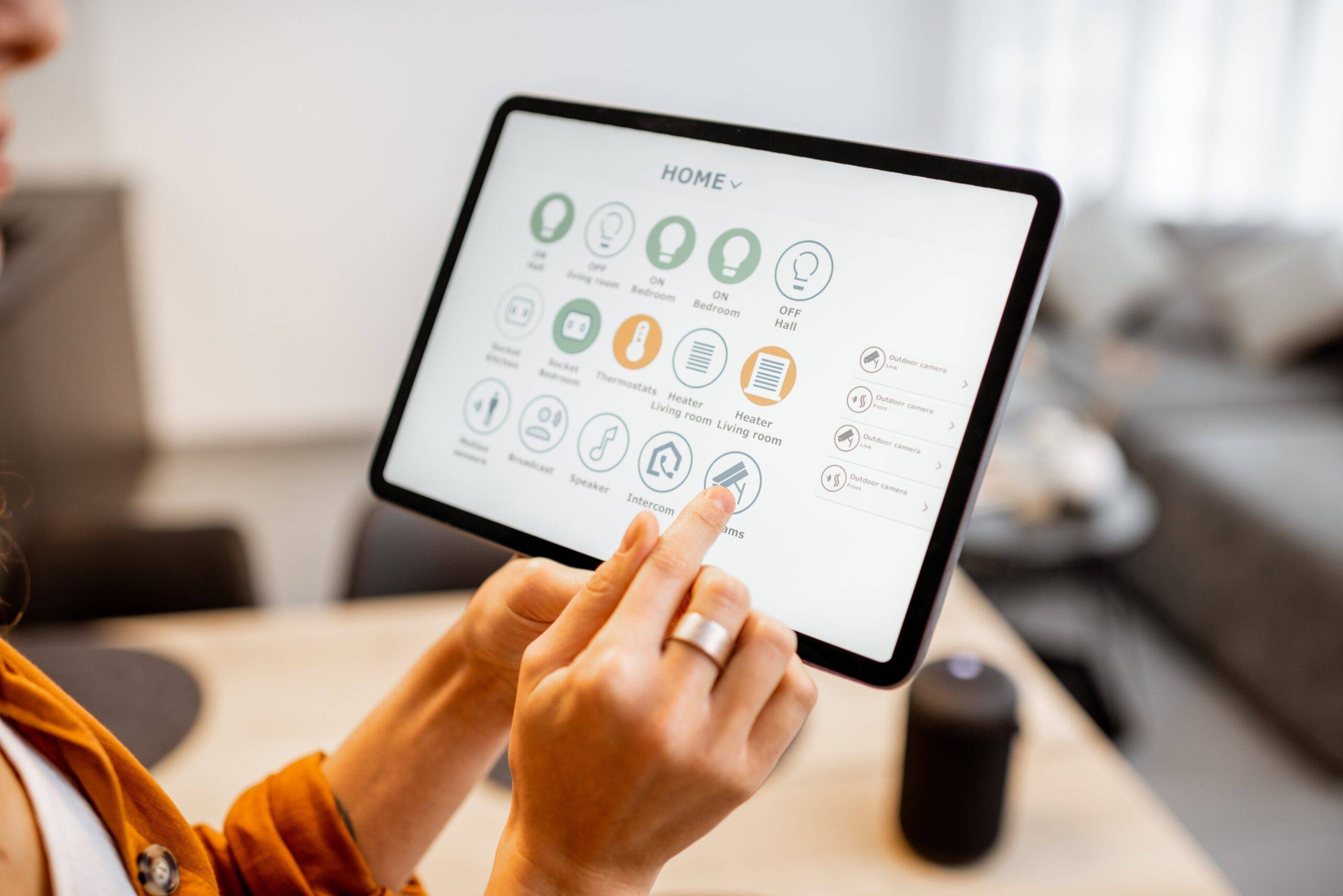 A woman holding up a tablet with a number of smart home controls up on the screen.