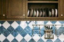 A close photo of some upper cabinets and the backsplash beneath them, white and blue diamond tiles.