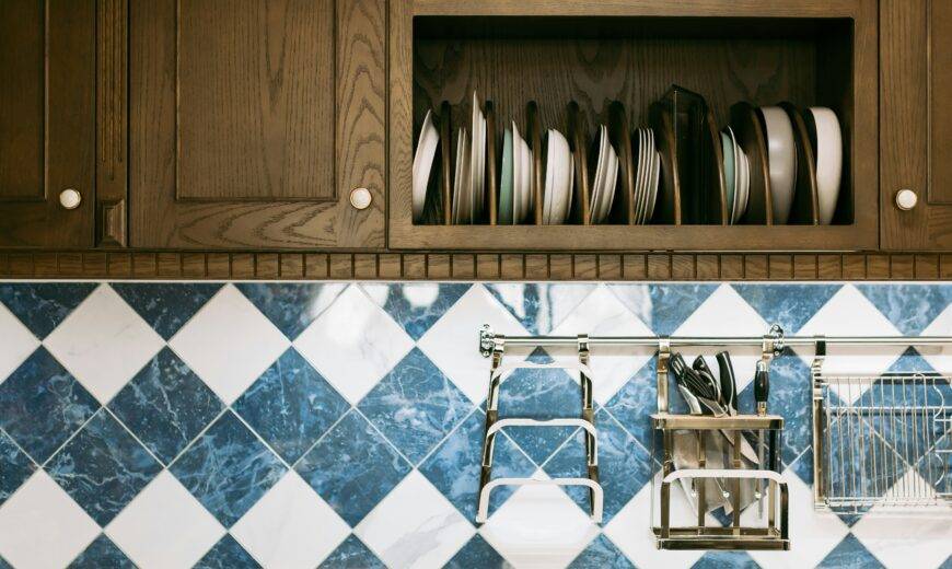 A close photo of some upper cabinets and the backsplash beneath them, white and blue diamond tiles.