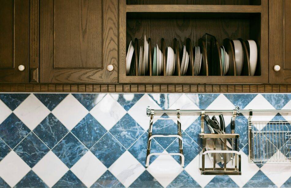 A close photo of some upper cabinets and the backsplash beneath them, white and blue diamond tiles.