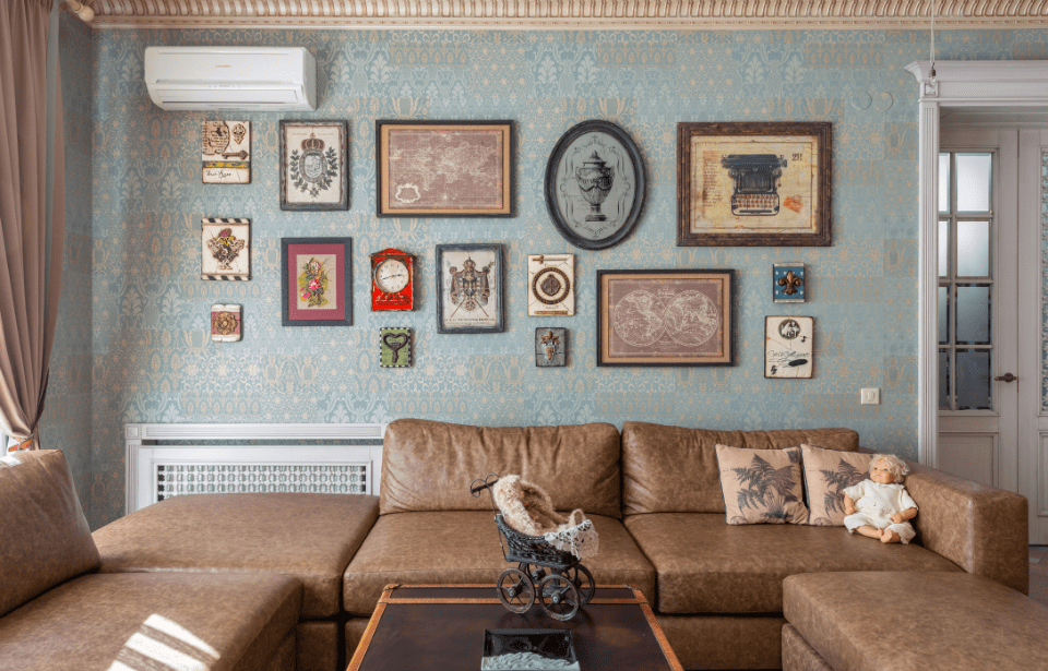 A wall above a living room sectional full of quirky, vintage wall art.