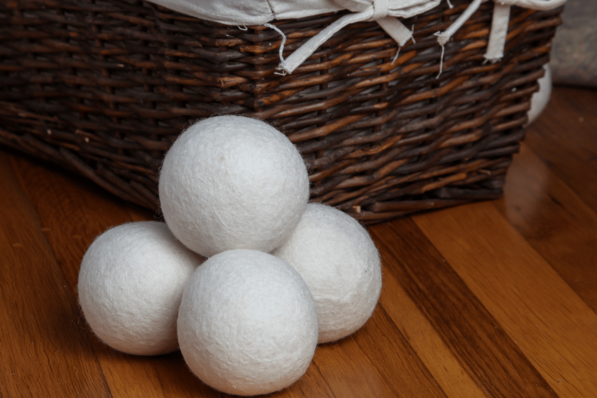 A stack of dryer balls next to a laundry hamper.