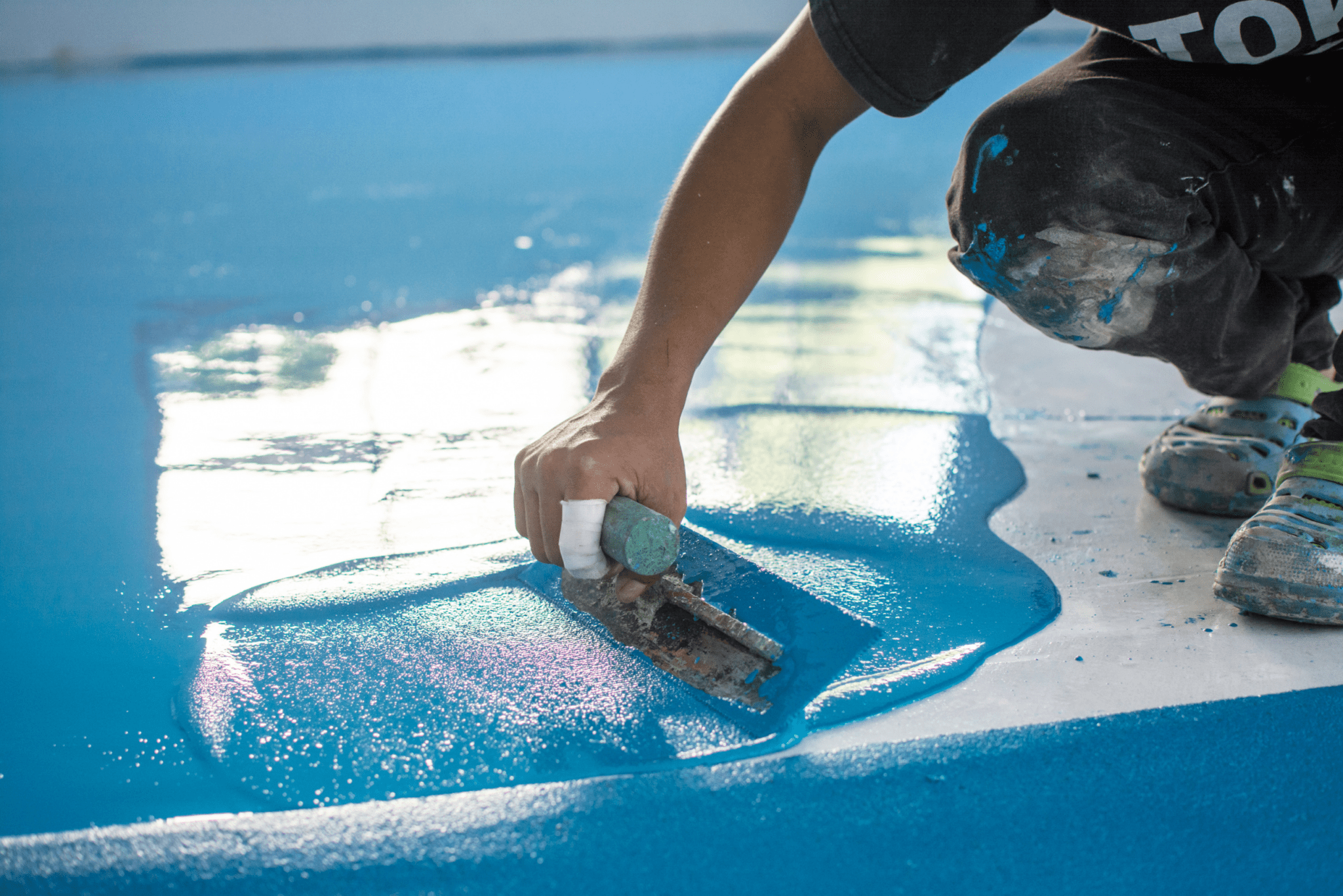 A man spreading a layer of textured liquid flooring composite.