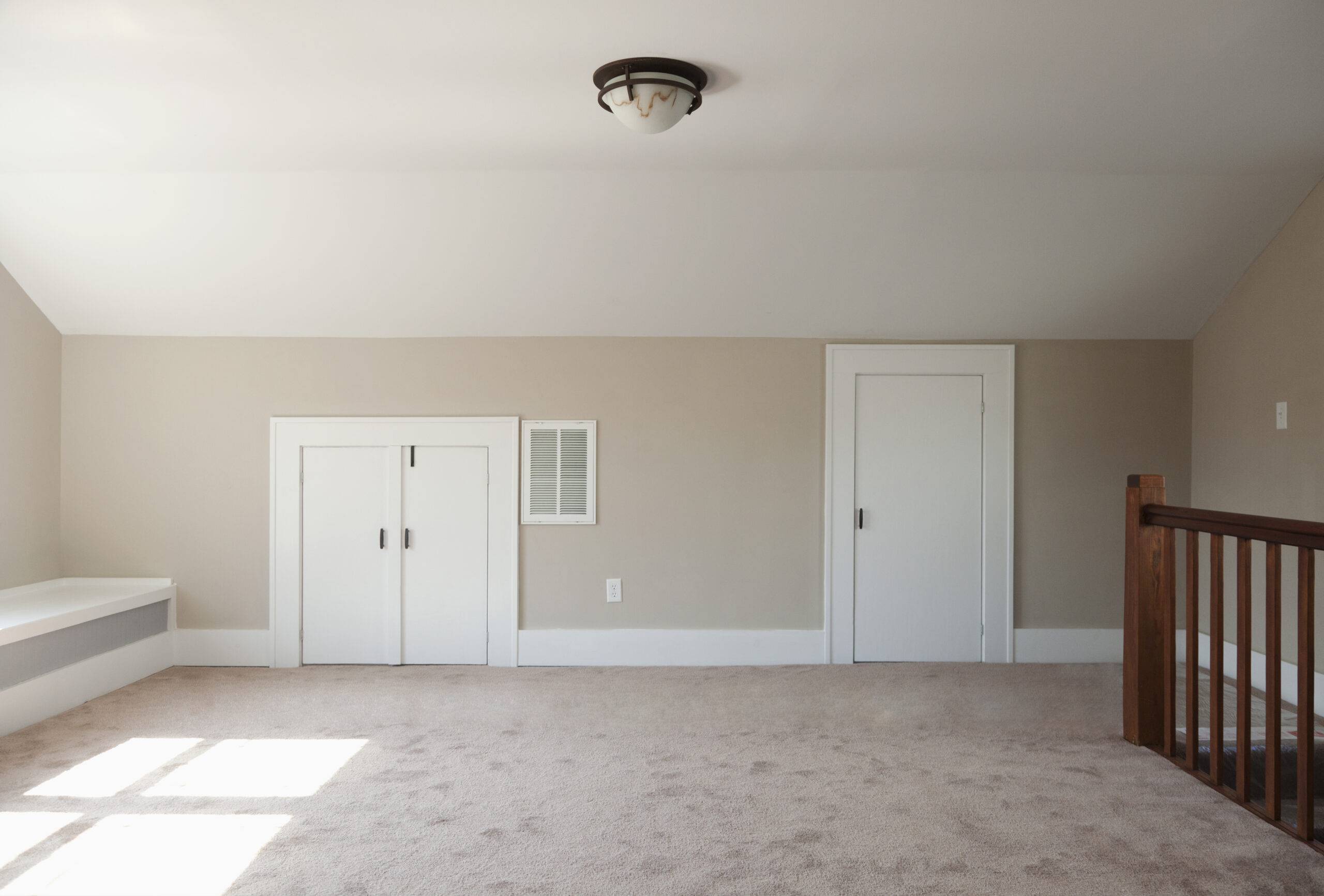 Empty attic room with beige walls, white trim and doors, carpeted floor, and a white ceiling.