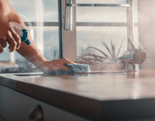 Someone spraying down a counter with a cleaner, rag in the other hand wiping it all down.