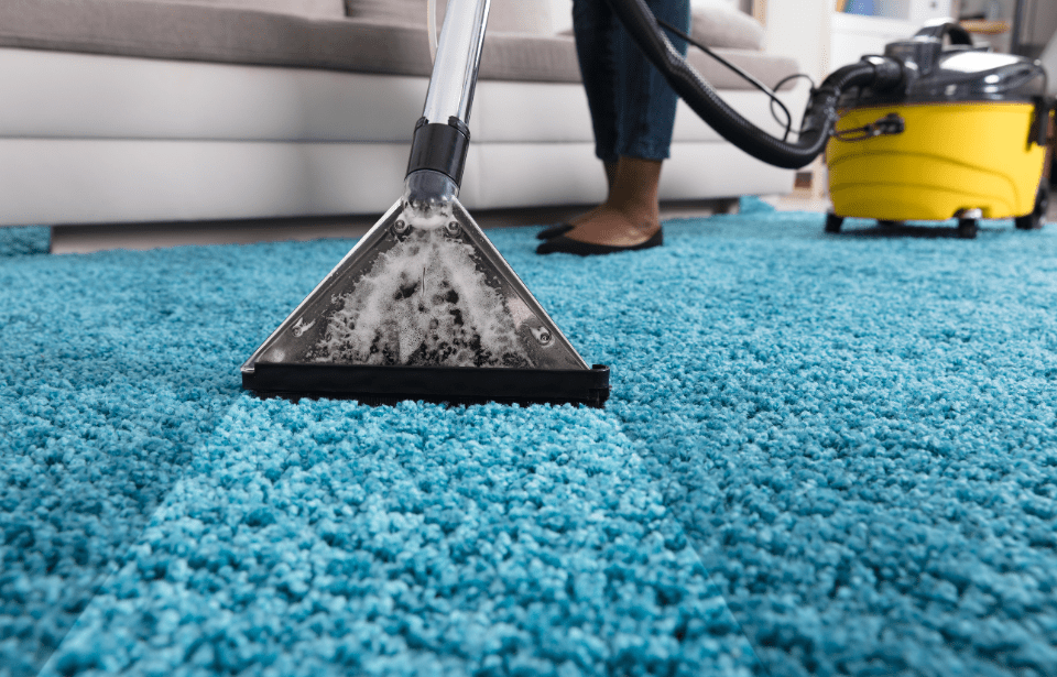 A close photo of someone cleaning a carpet with a carpet cleaner.