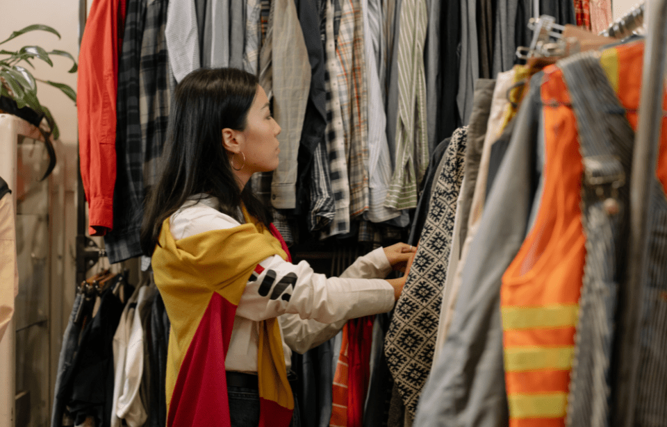 A woman looking through racks of clothes.