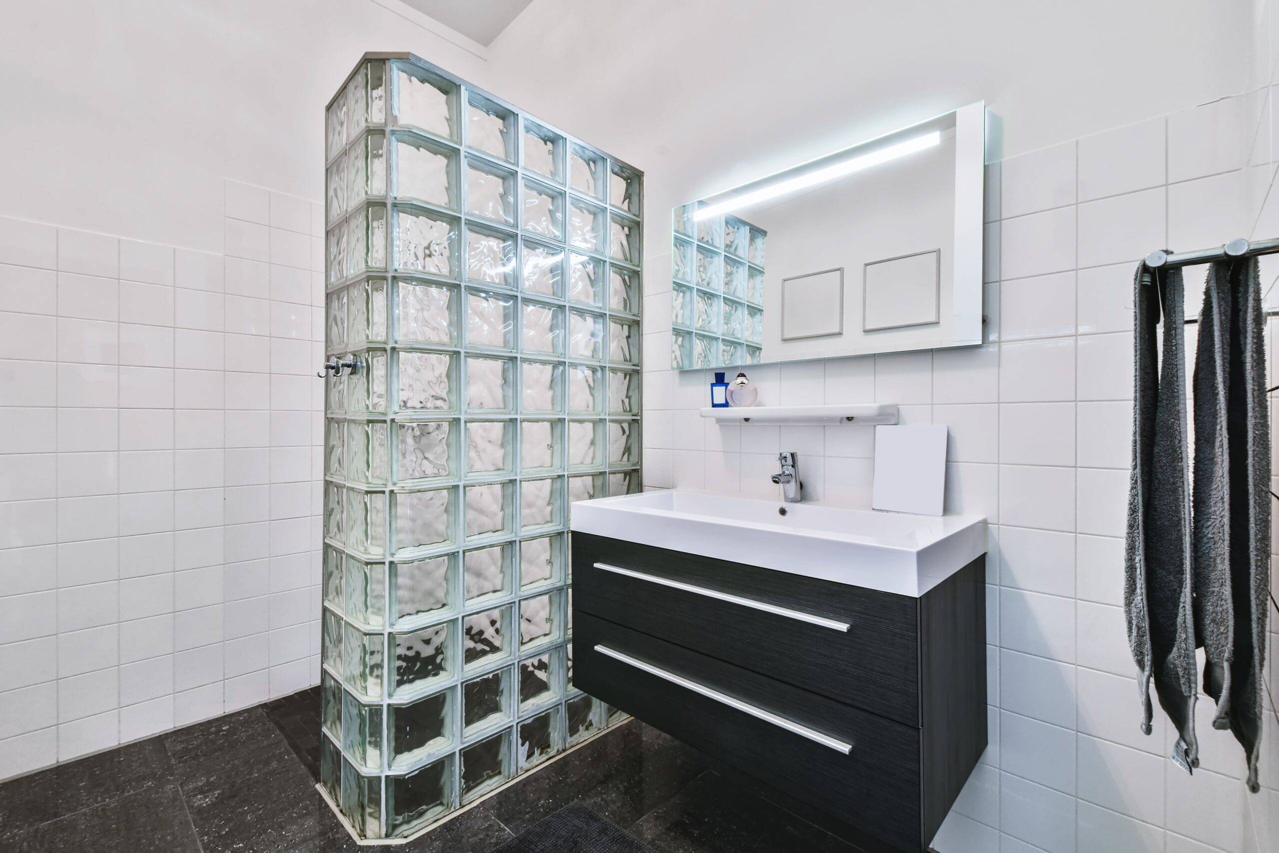 A bathroom with a wall of tiled glass between the sink and toilet.