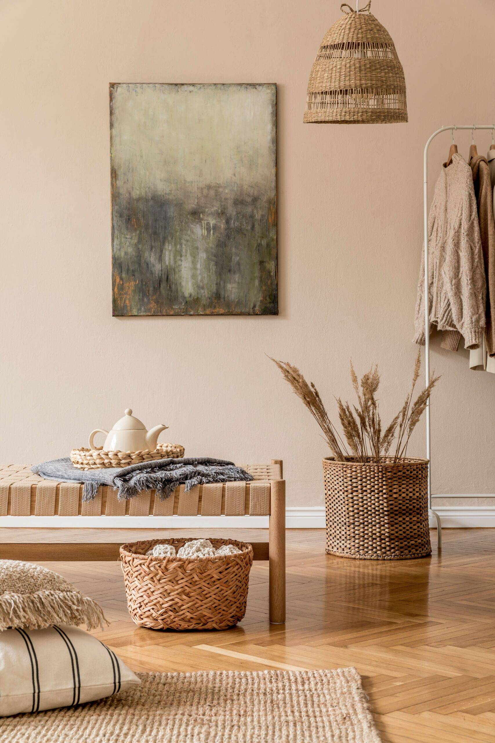 A frame of a room that features a lot of brown tones, natural fibers/materials, some wicker decor and plenty of blankets/clothes hung up.