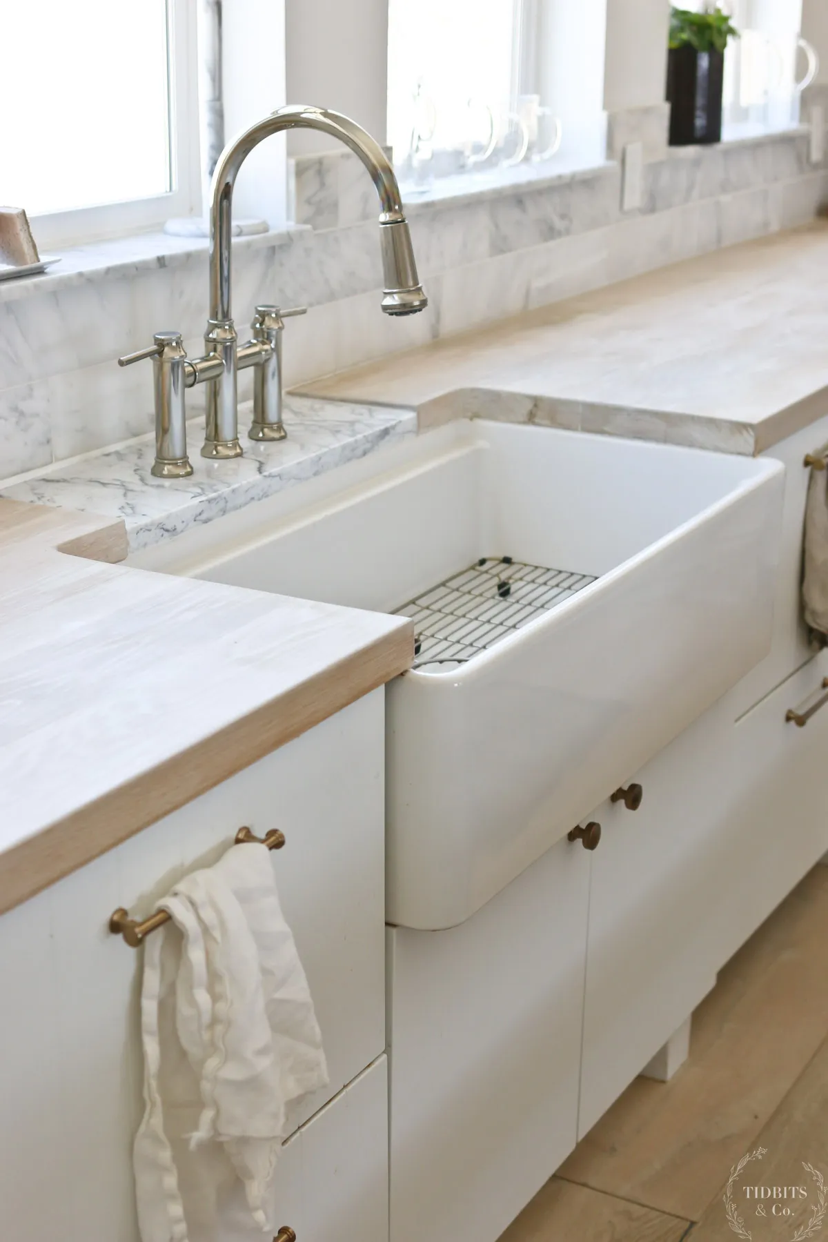 A farmhouse sink in the middle of a whitewashed butcher block countertop.