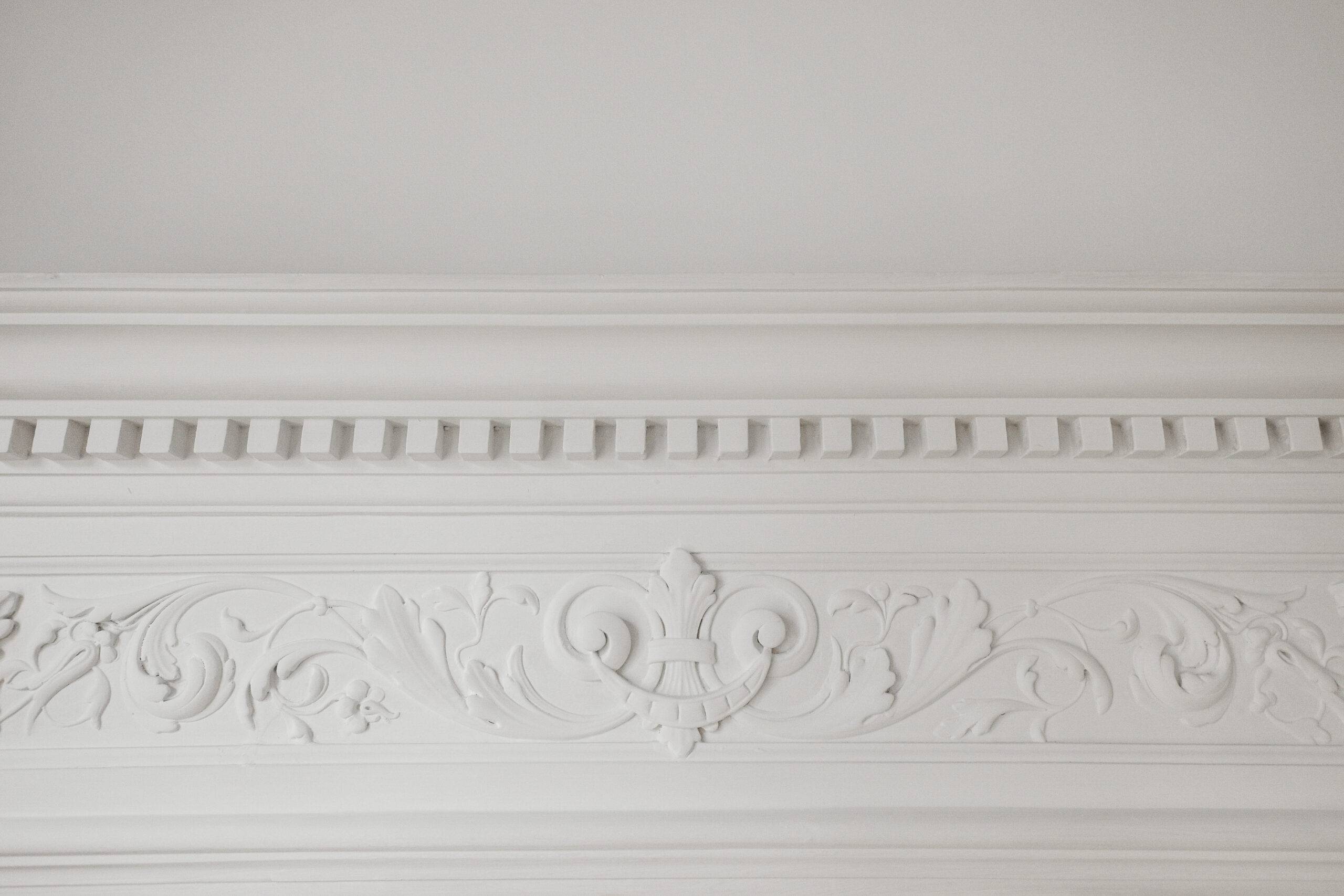 Decorative clay stucco relief molding with ornaments on white ceiling in abstract classical style interior