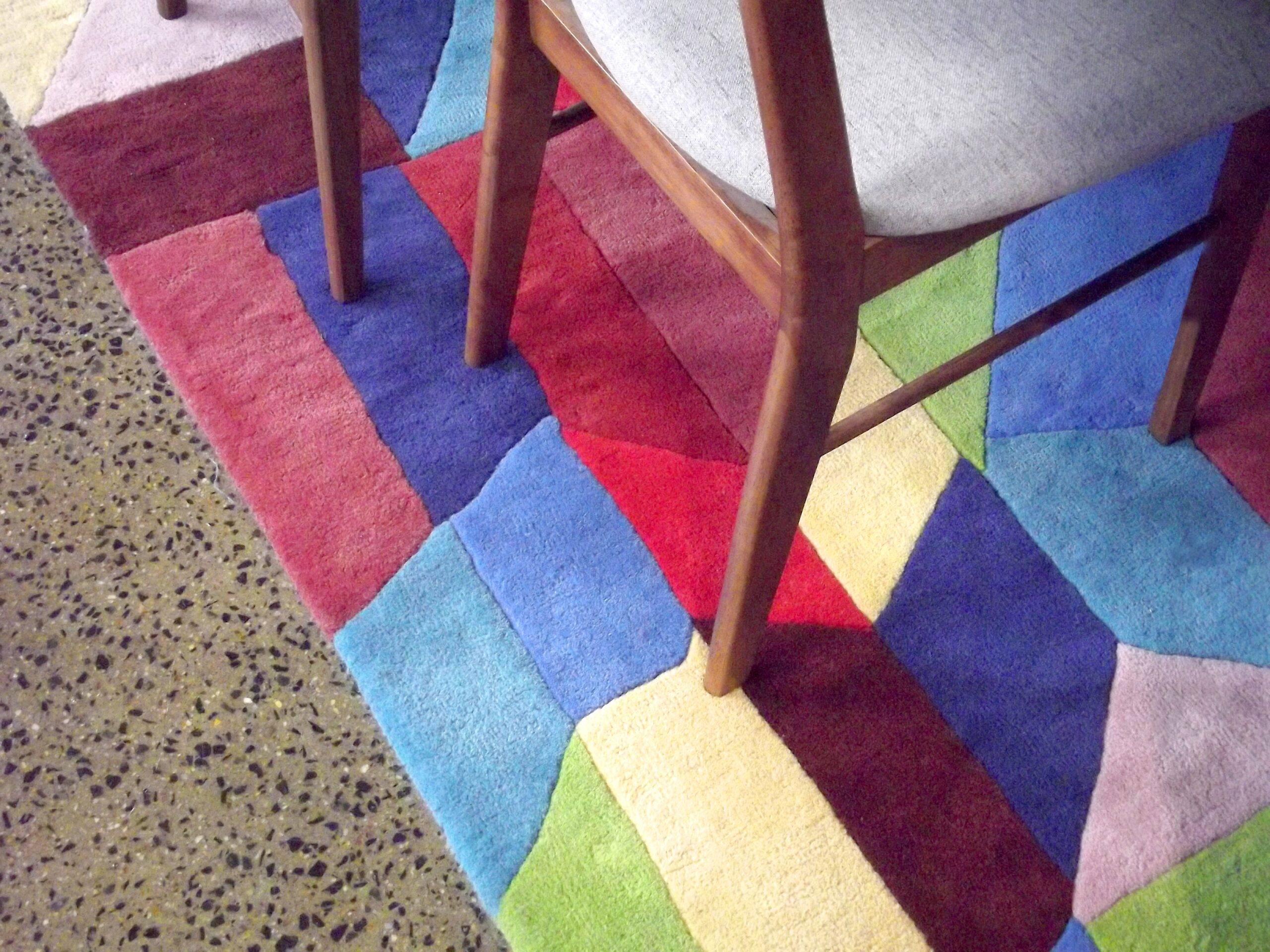 A colorful geometric rug beneath the feet of some chairs.