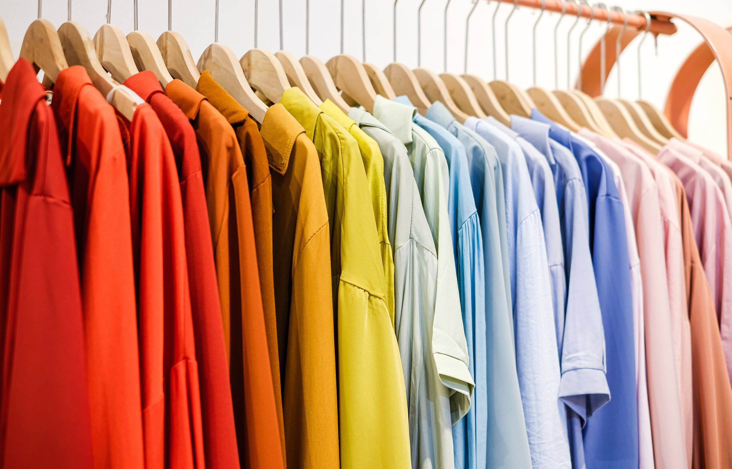 A rack of clothes on hangers, all color coordinated.