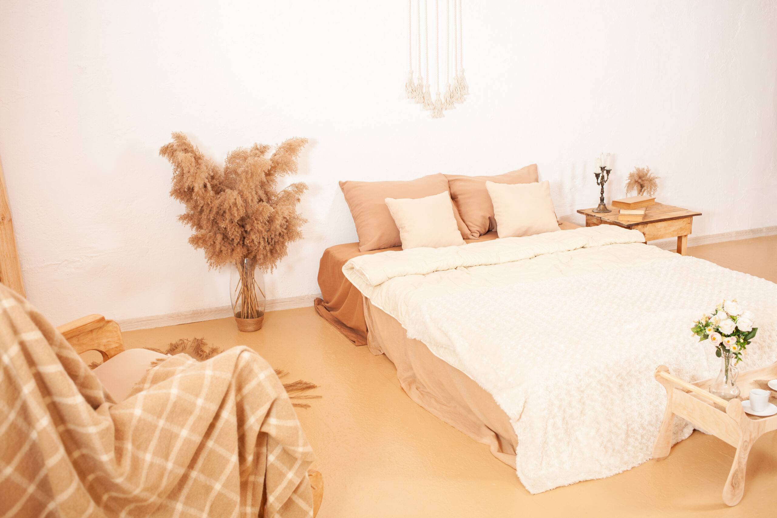 Beige brown white interior. Bedroom of light shades. A rocking chair with a plaid, a mirror in a wooden frame, flowers pampas plant. Decorations for the house DIY. Fashion design.