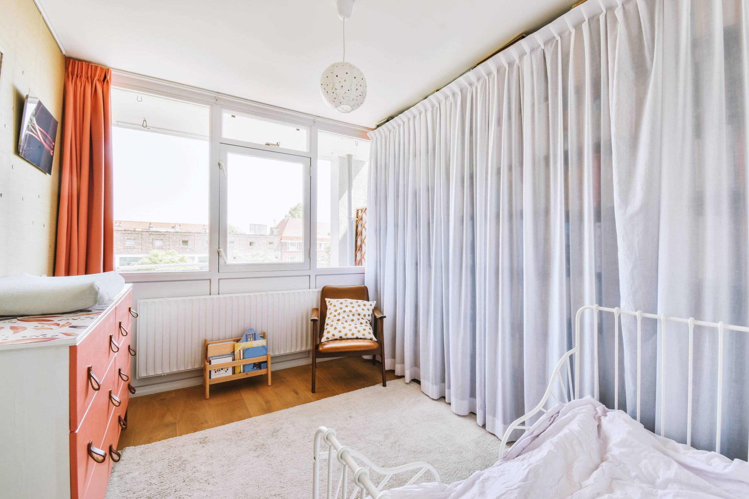 Home interior design of bedroom with bed and wooden wardrobe placed in corner near window in modern apartment