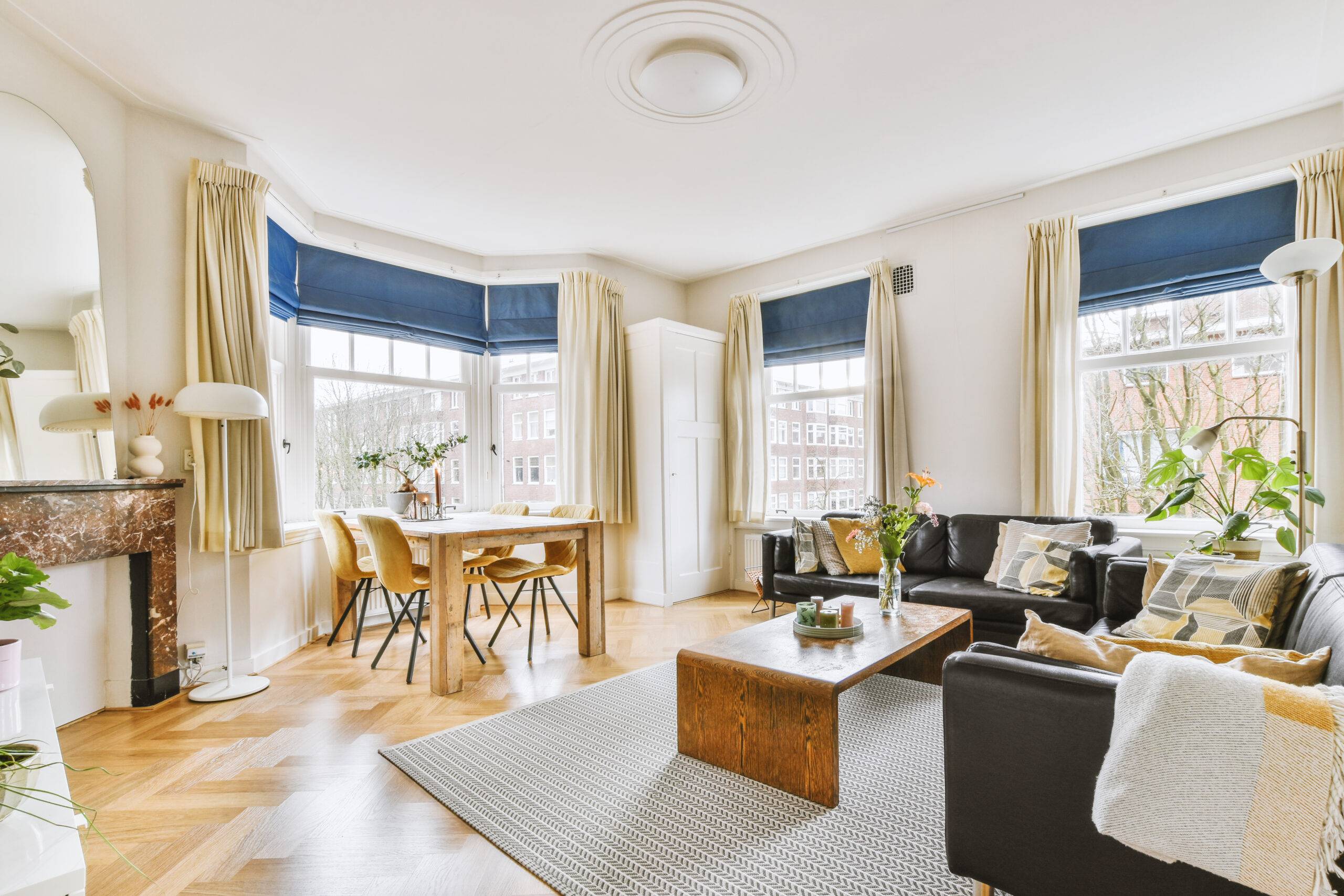 Shabby wooden table with chairs and vase located near comfortable couch against light walls with decorations and TV in modern apartment