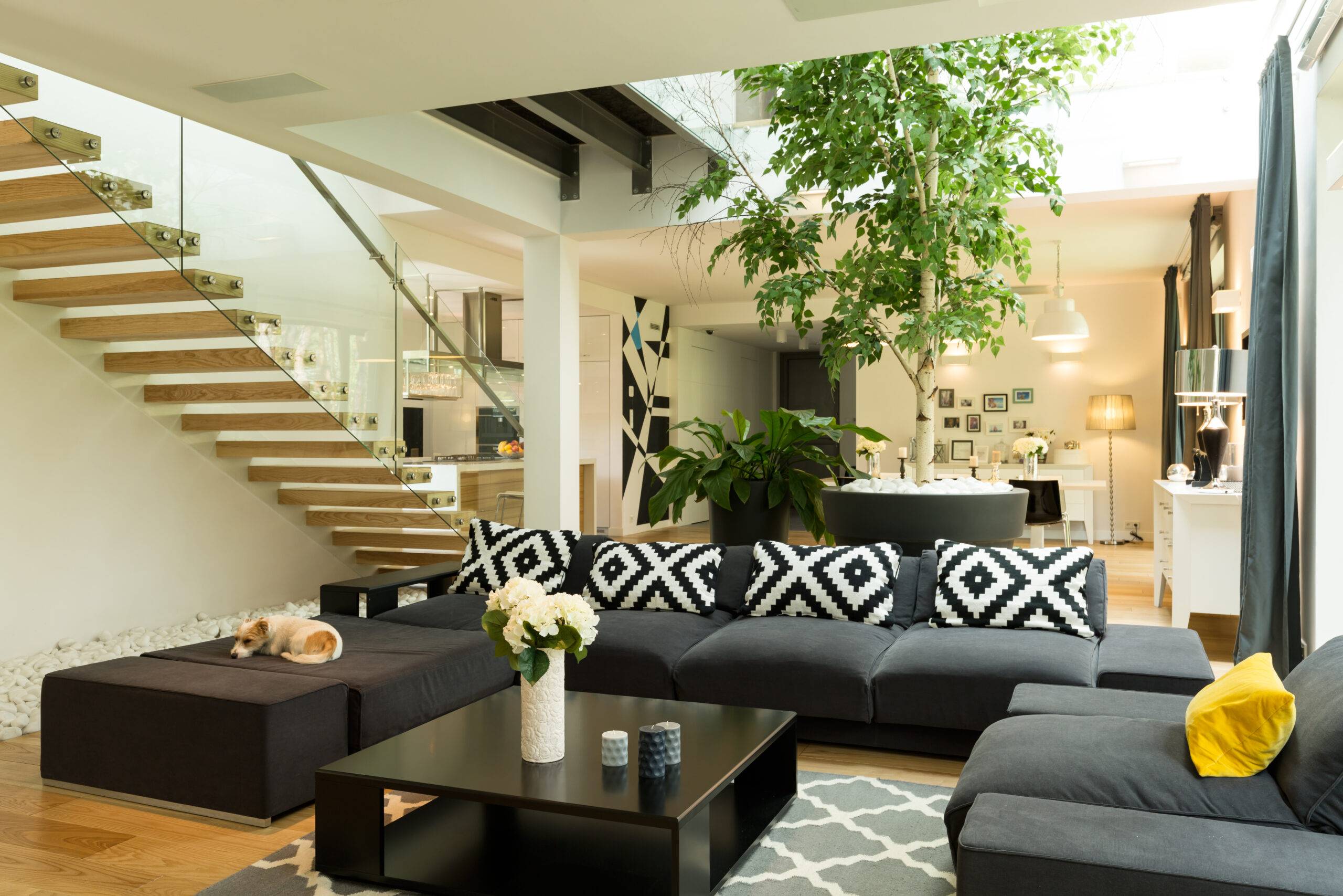 Living room with black sofa, patterned pillowes and coffee table open to the staircase