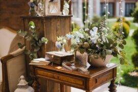 A collection of vintage decor items and greenery on a small antique table.