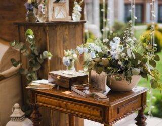 A collection of vintage decor items and greenery on a small antique table.