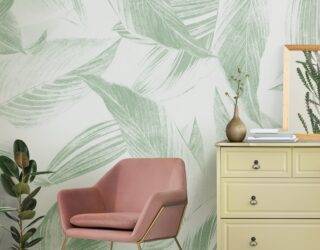 A section of a living room, zooming in on a chair and dresser with accessories, a large print leafy wallpaper behind.