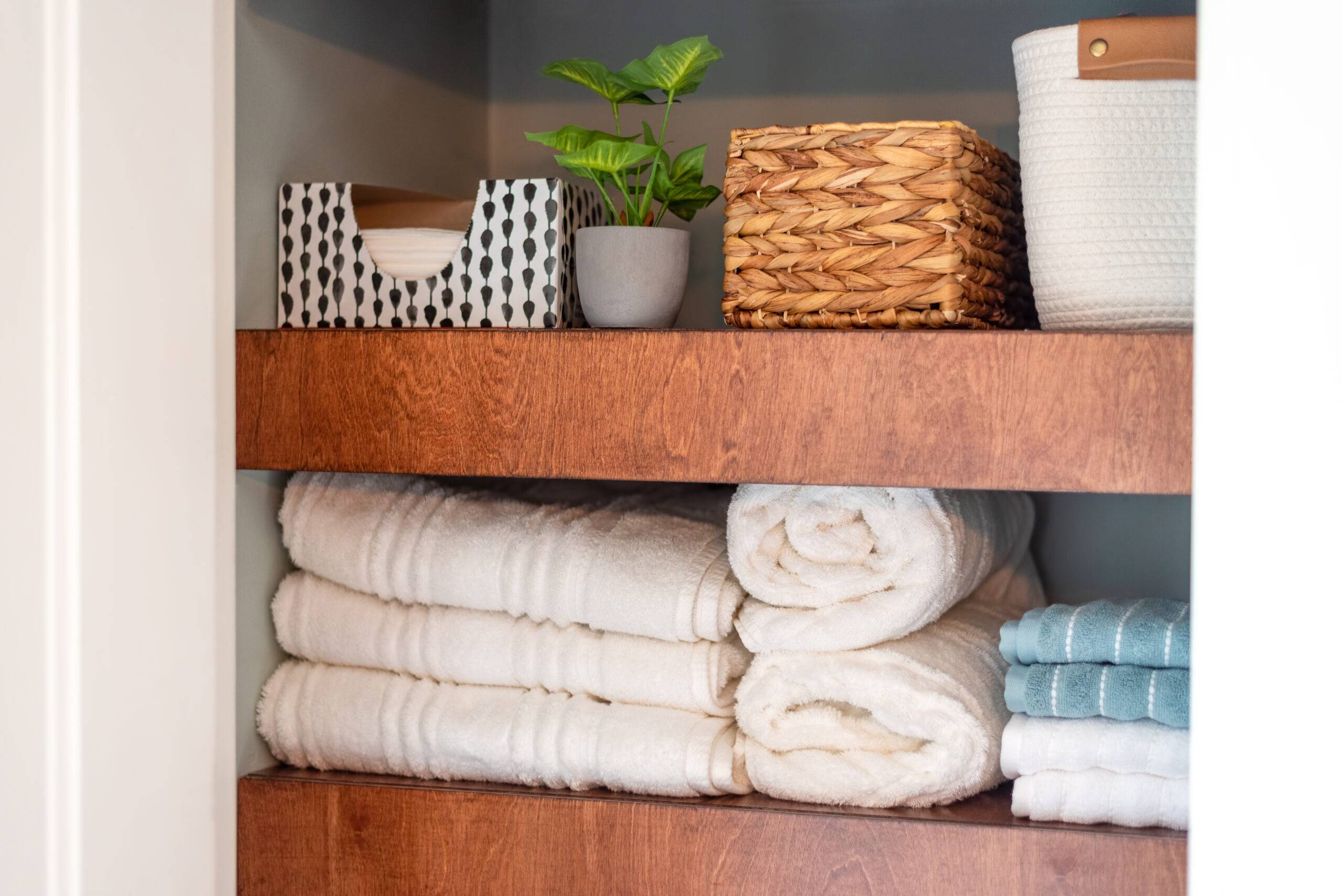 Neatly organized bathroom closet with floating wood shelves