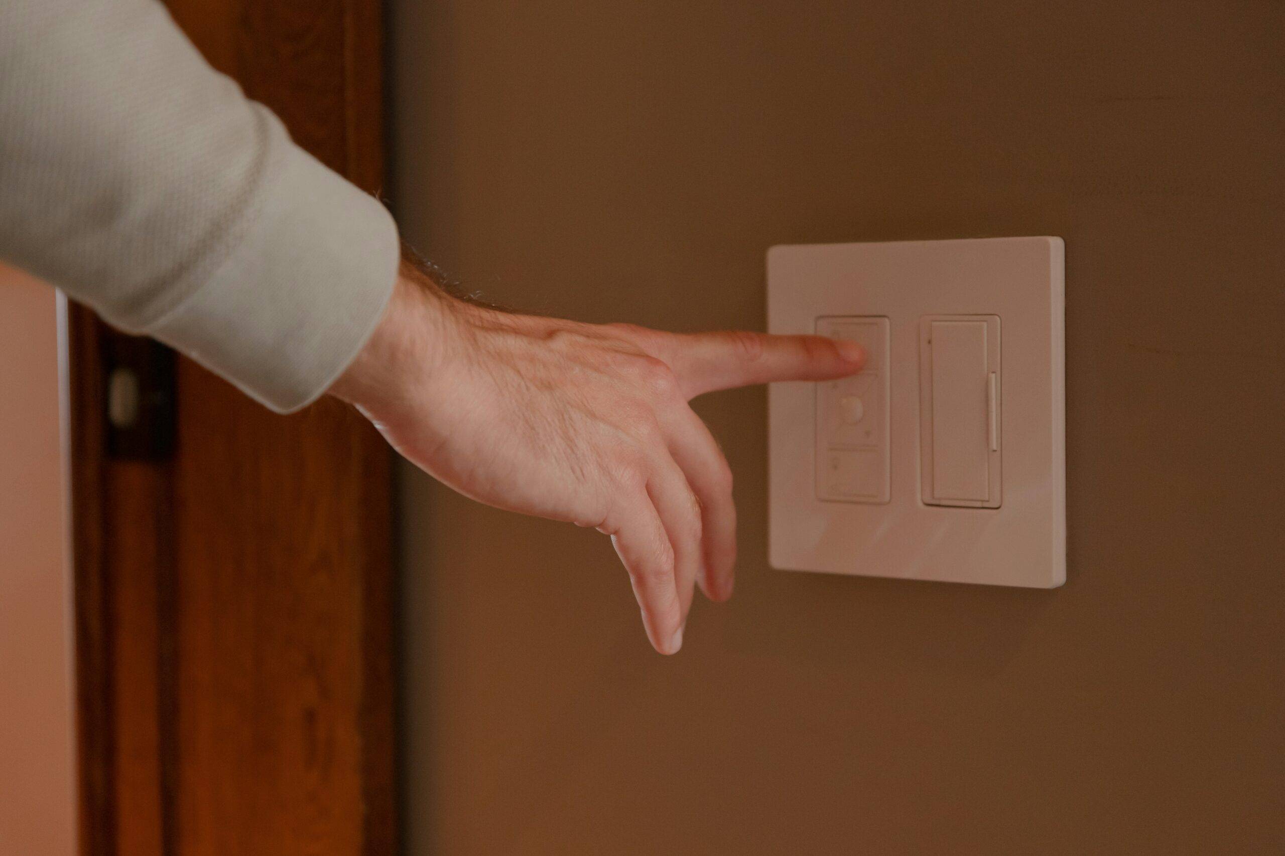 A hand reaching out to flip a light switch.