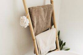 A bamboo towel ladder against a bathroom wall, holding towels.