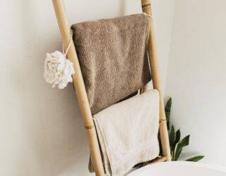 A bamboo towel ladder against a bathroom wall, holding towels.