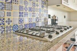 A stove with a busy tile backsplash behind it.