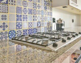 A stove with a busy tile backsplash behind it.