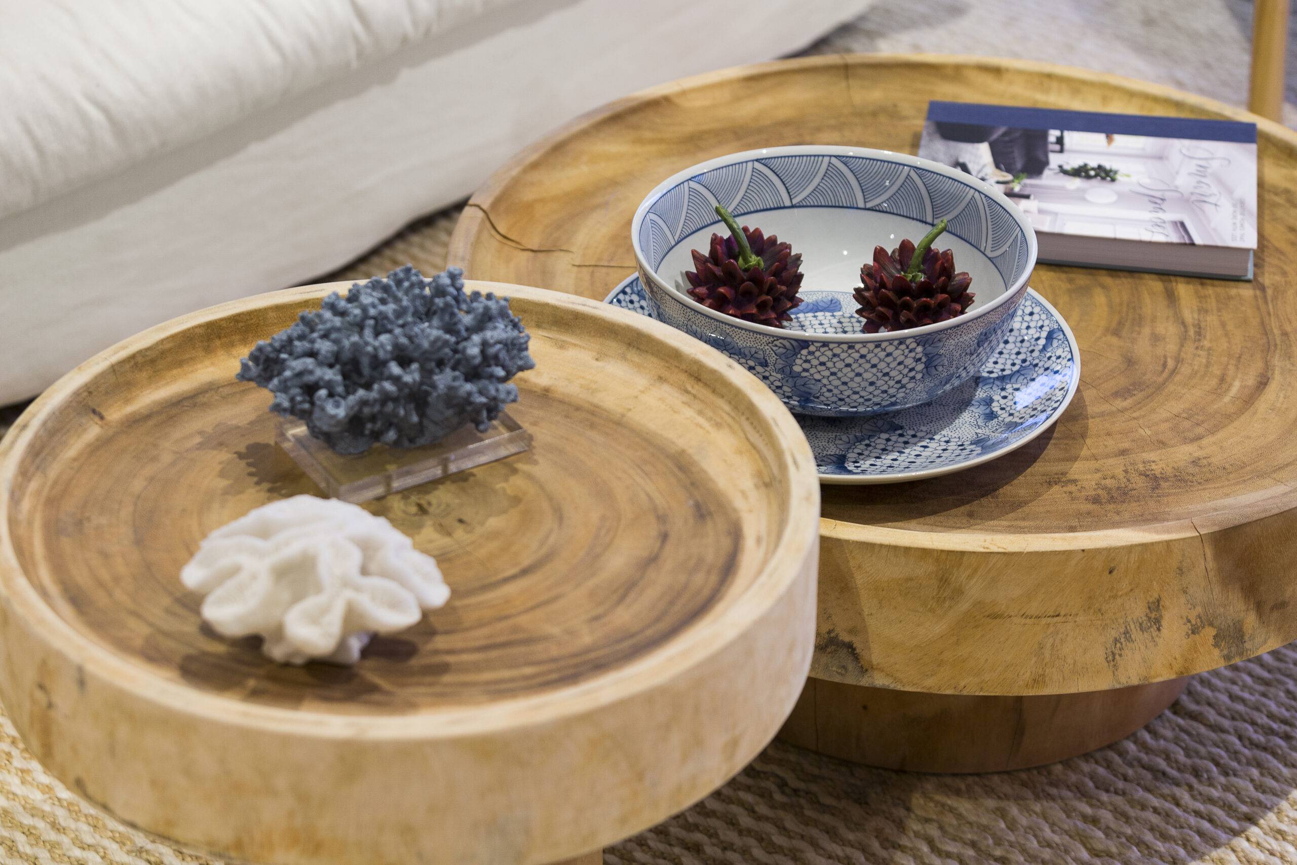 A two-tiered wooden coffee table with some decorative items, including a ceramic bowl.