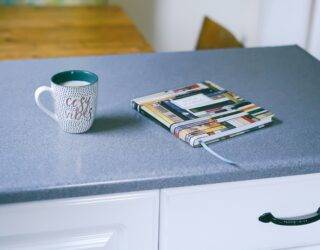 A kitchen counter with a mug and journal on it.