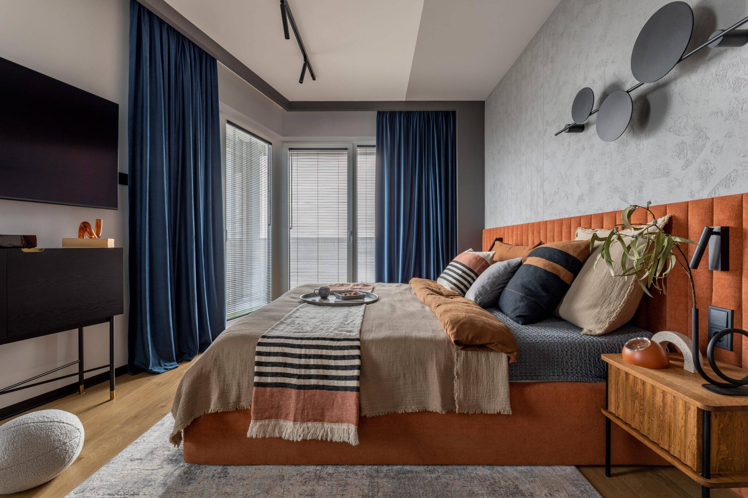 A bedroom with a large bed decorated with orange and blue linens.