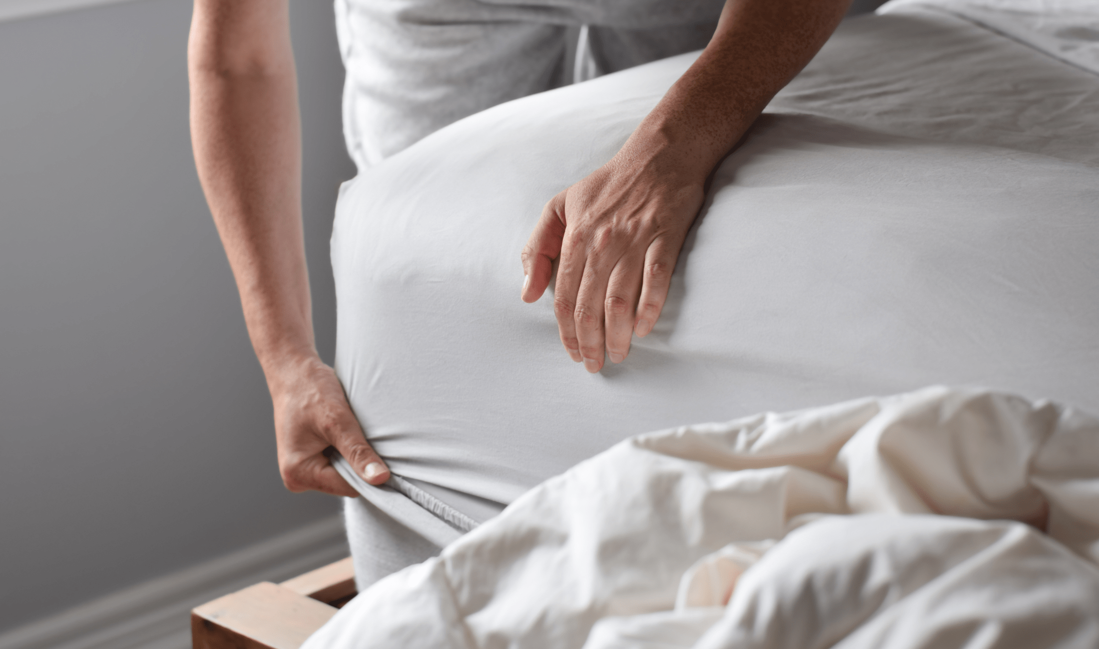 A closeup of someone tucking in a fitted sheet.