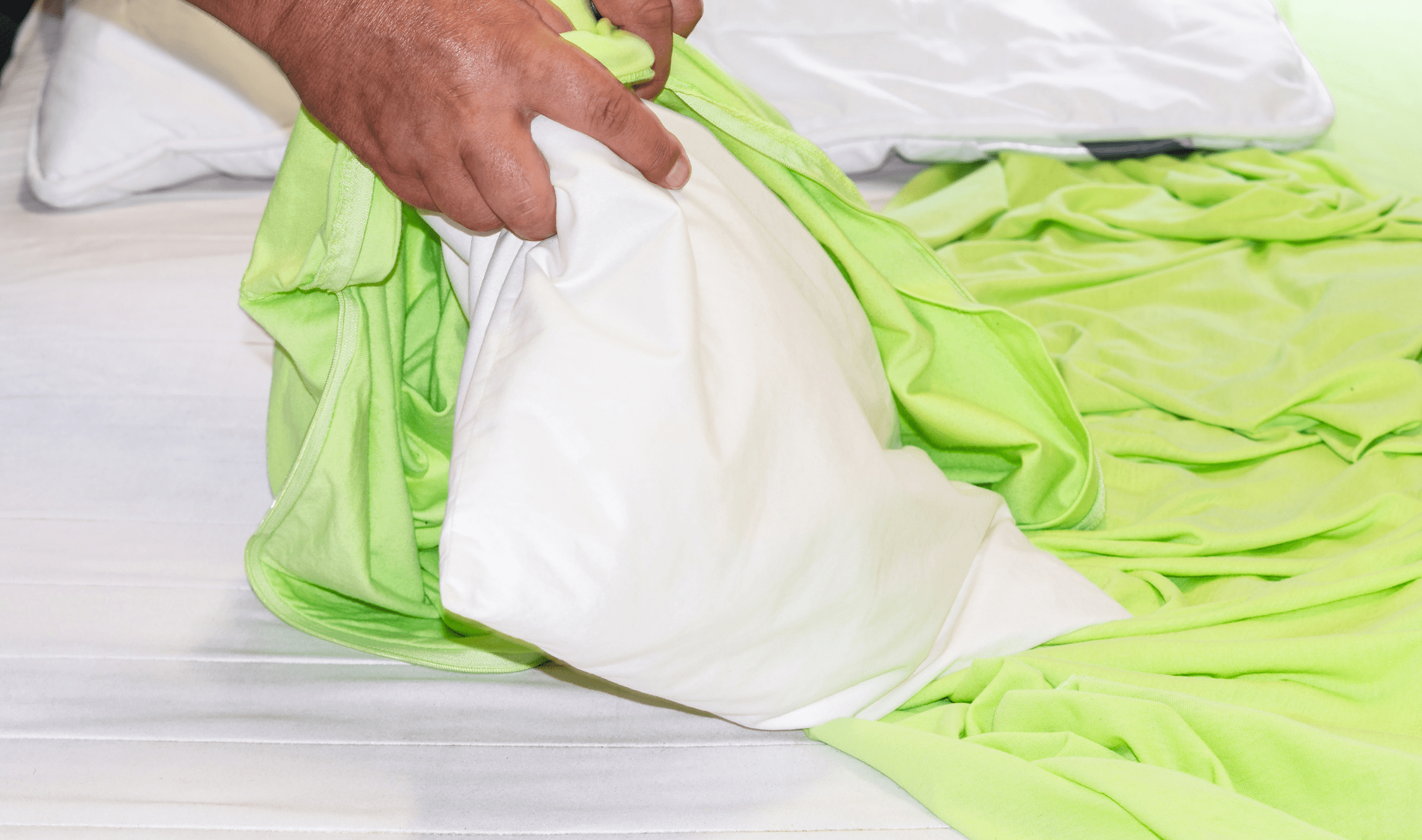 A closeup of someone putting a duvet into a bright green duvet cover.