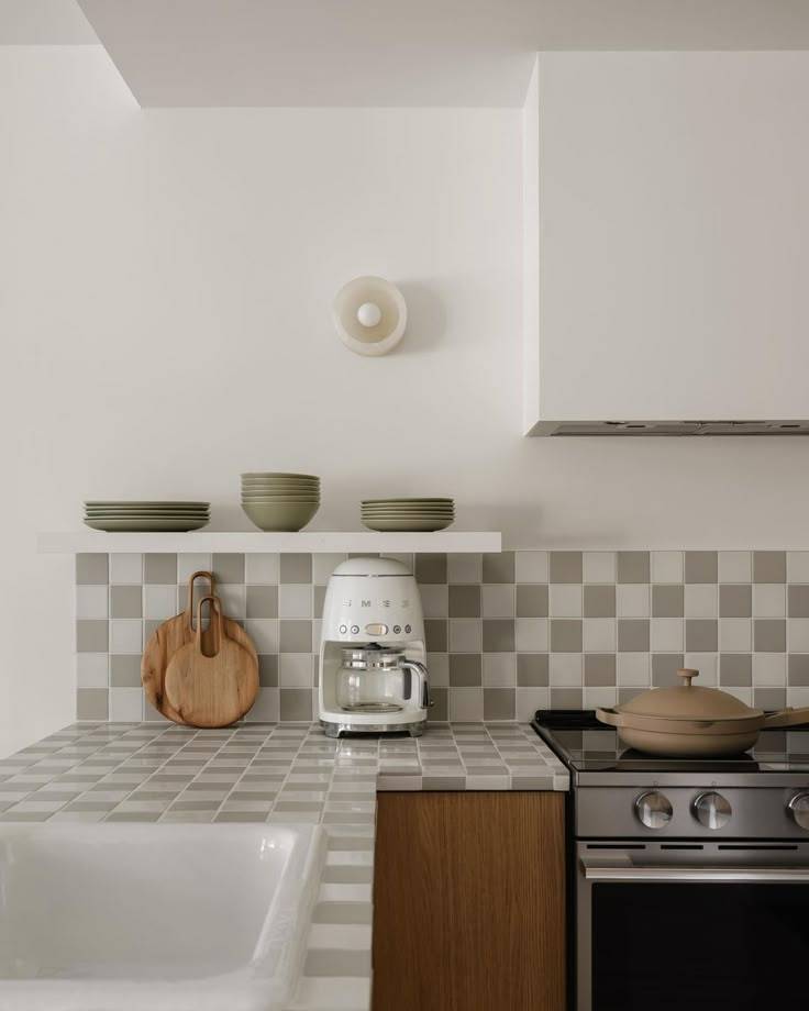 A kitchen woith white and light green checkerboard tiled countertops.