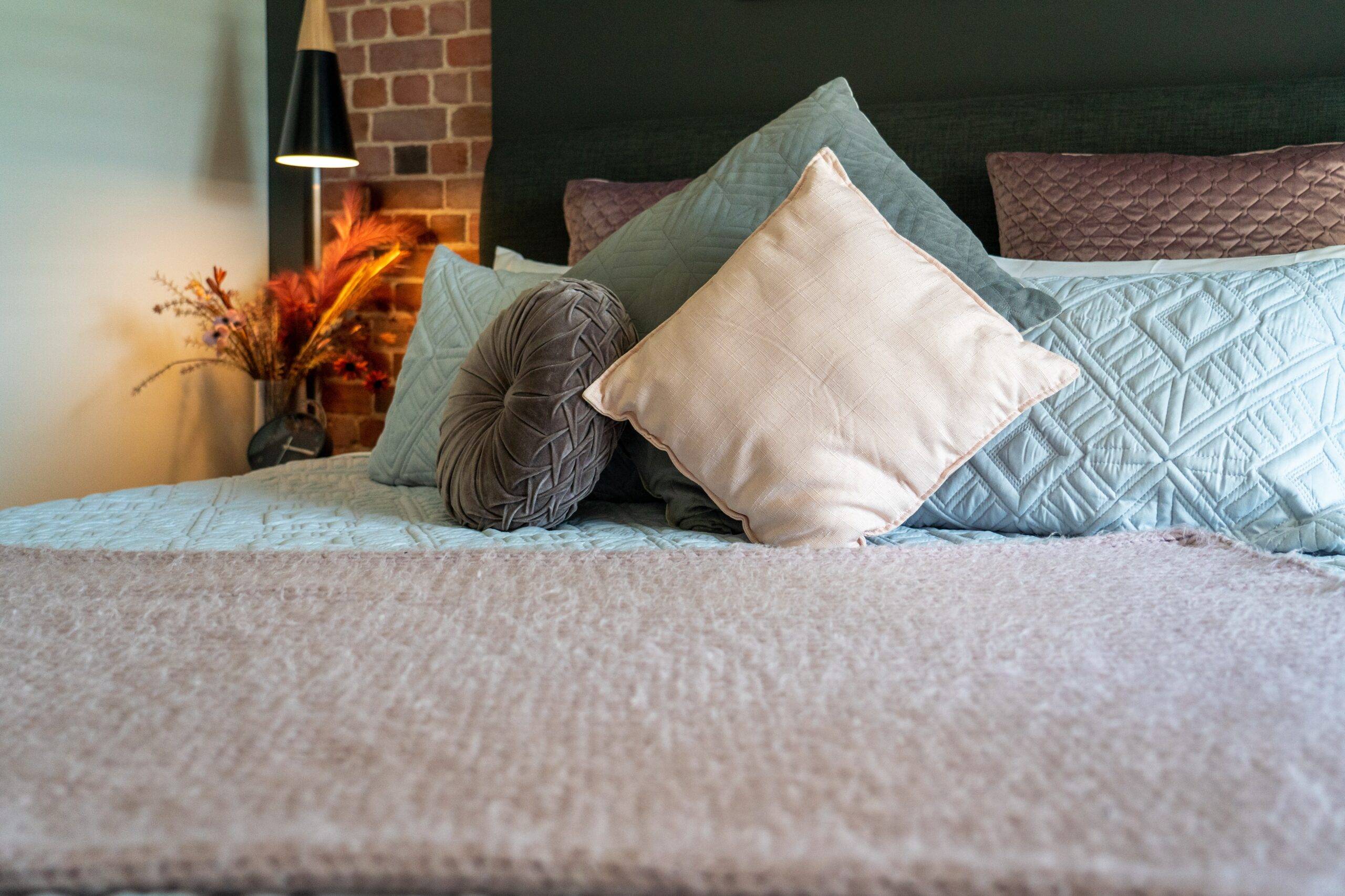 A bed with soft throw pillows and blankets on it.