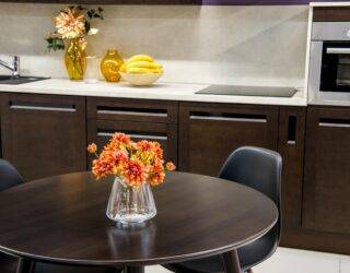 A modern kitchen with dark wood cabinets and dining table.