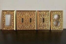 An assortment of gold light switch covers with intricate embossed patterns.