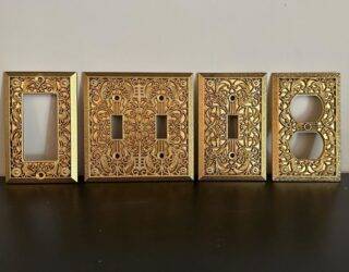 An assortment of gold light switch covers with intricate embossed patterns.