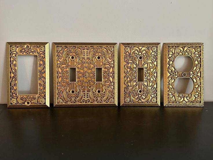 An assortment of gold light switch covers with intricate embossed patterns.