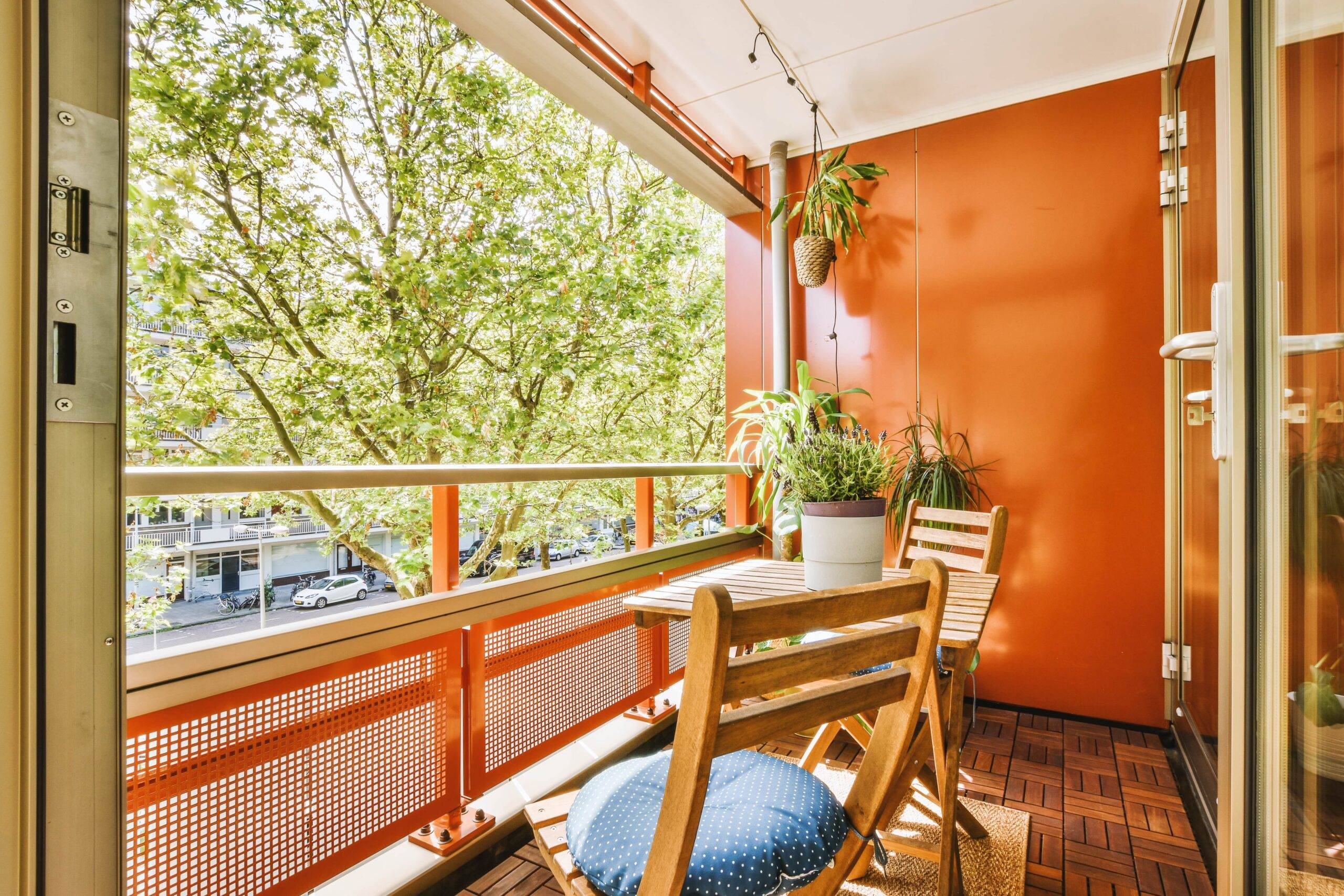 A small balcony colored orange with plenty of plant life.