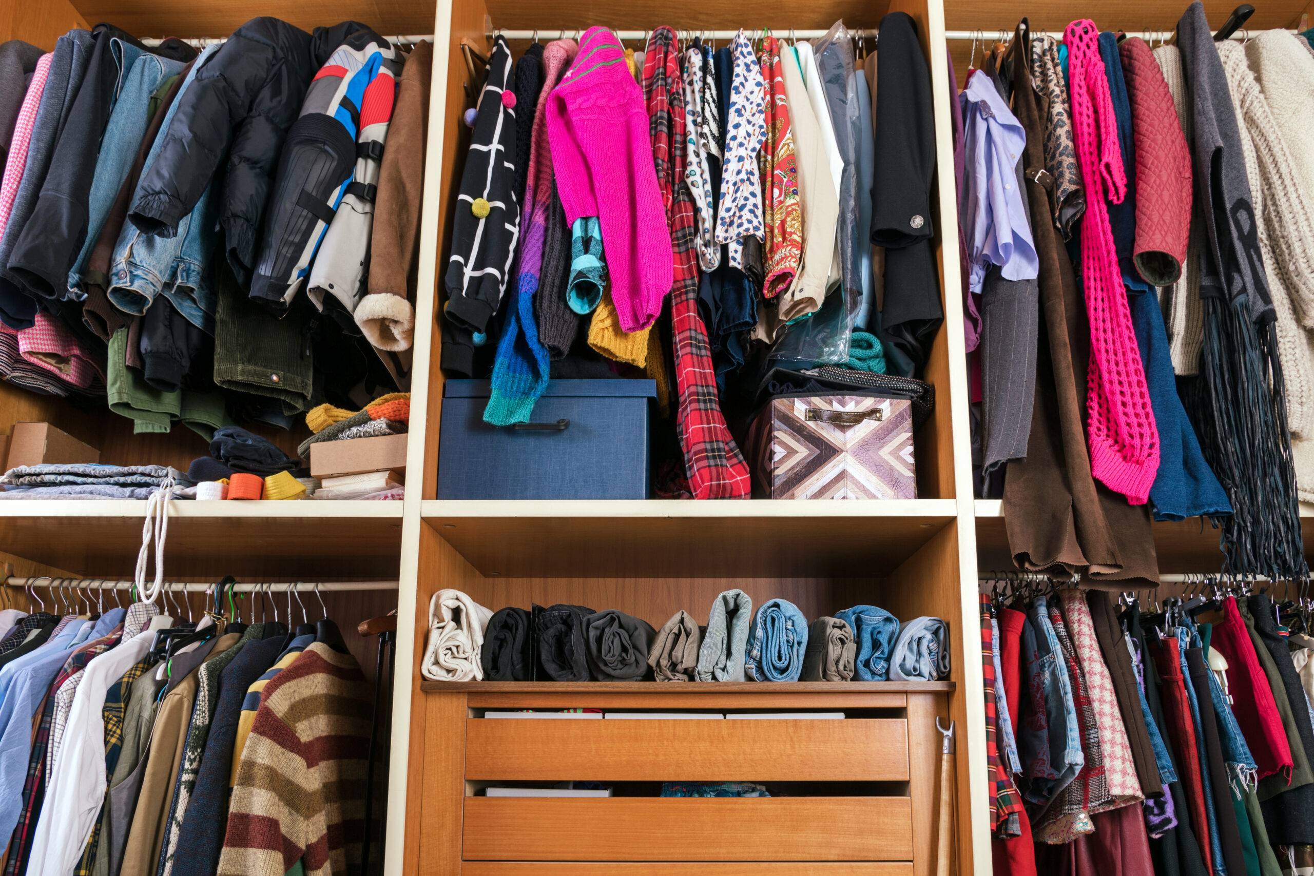 Collection of multicolored assorted clothes placed accurately on rails and hangers with shelves in walk in closet