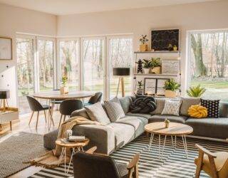 A large, modern living room featuring an L couch and dining table behind it.