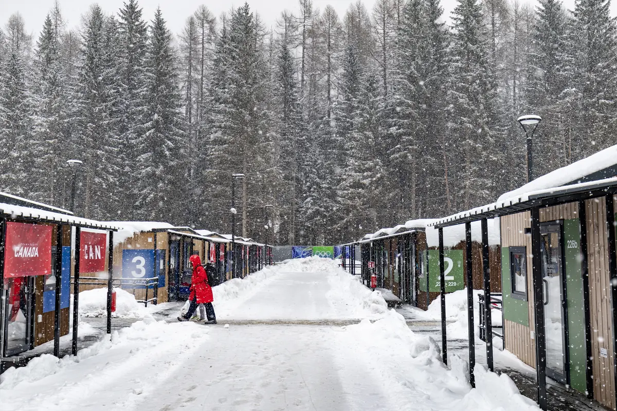 Snow falls as athletes walk at the Olympic Village ahead of the Milano Cortina 2026 Winter Olympics in Cortina d'Ampezzo